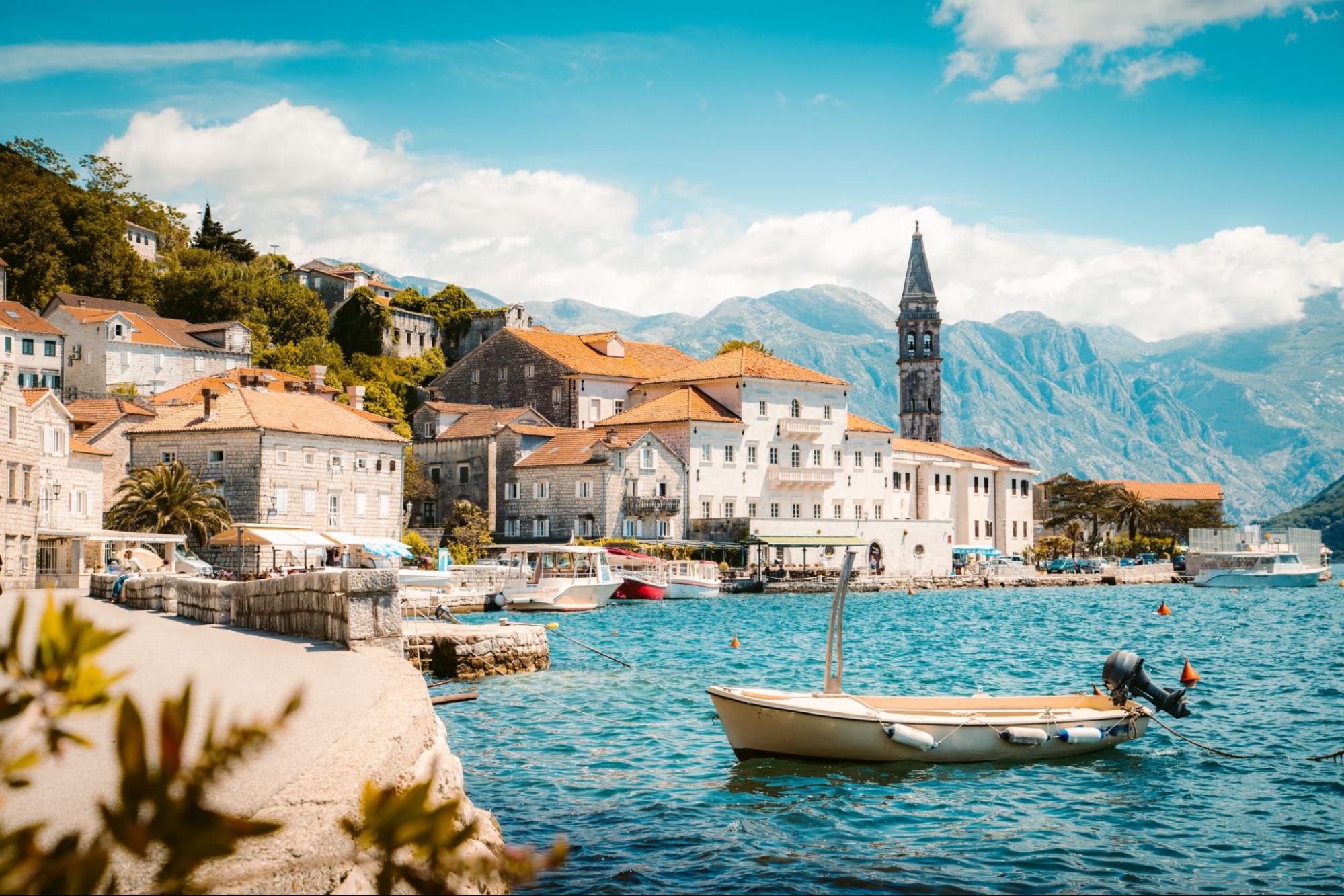 Classic panorama view of the historic town of Perast located at world-famous Bay of Kotor on a beautiful sunny day with blue sky and clouds in summer, Montenegro, southern Europe.